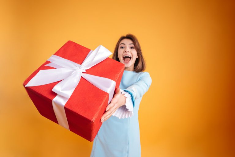 Happy excited young woman giving you gift box